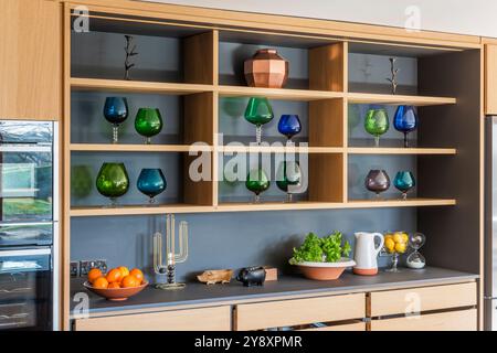 Verrerie sur étagères dans une cuisine design moderne dans le Gloucestershire, Angleterre, Royaume-Uni Banque D'Images