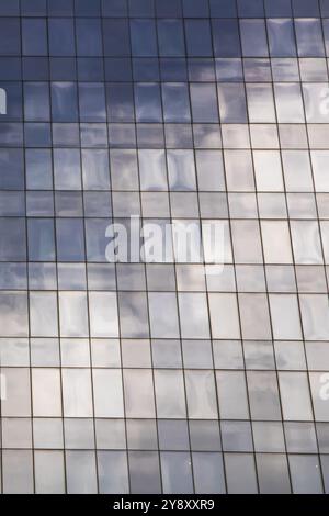 Un bâtiment reflète un ciel bleu dans ses fenêtres, avec une forme rectangulaire, des couleurs grises, des matériaux composites, du bois, des teintes, nuances, motifs, symétrie Banque D'Images