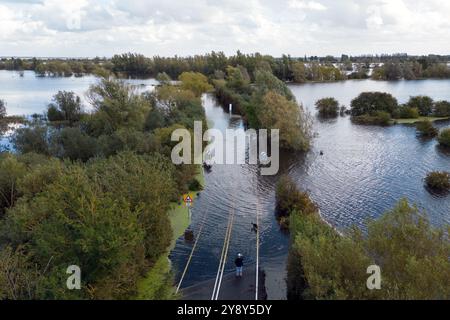 Un résident local vérifie l'A1101 à Welney dans le Norfolk qui est submergée par les inondations de la rivière Old Bedford et de la rivière Delph, laissant les habitants face à une déviation de 35 miles. Les orages et les fortes pluies peuvent perturber les transports dans certaines parties du sud de l'Angleterre et du pays de Galles, après qu'un avertissement d'orage jaune ait été émis par le met Office lundi après-midi dans une grande partie du sud du pays de Galles, du sud-ouest de l'Angleterre et dans certaines parties du sud de l'Angleterre. Date de la photo : lundi 7 octobre 2024. Banque D'Images