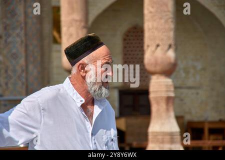 Boukhara, Ouzbékistan ; septembre,19,2024:gros plan d'un homme ouzbek habillé en blanc, portant le chapeau traditionnel Tyubeteika à Boukhara, Ouzbékistan. Banque D'Images