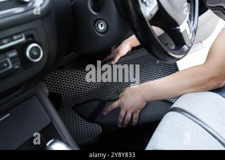 Homme prenant tapis de voiture en caoutchouc gris de l'auto, gros plan Banque D'Images