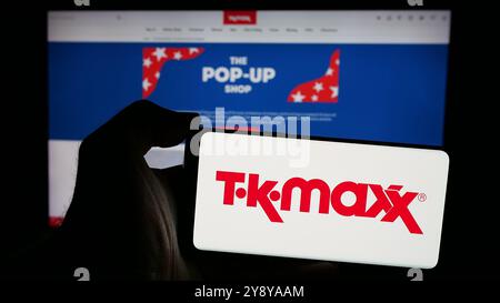 Personne tenant le smartphone avec le logo de la société de vente au détail TK Maxx sur l'écran en face du site Web. Concentrez-vous sur l'affichage du téléphone. Banque D'Images