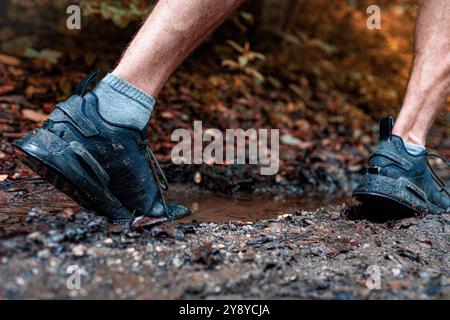 Coureur de trail masculin hors route qui court sur un sentier forestier boueux Banque D'Images