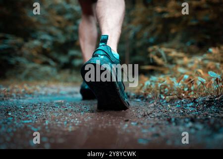 Jambes de coureur masculin athlétique construit courir sur un sentier forestier boueux Banque D'Images