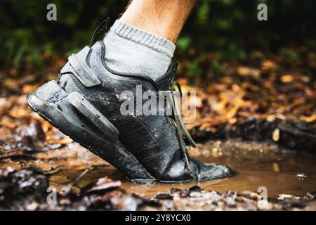 Gros plan. Chaussures de trail running dans la flaque Banque D'Images