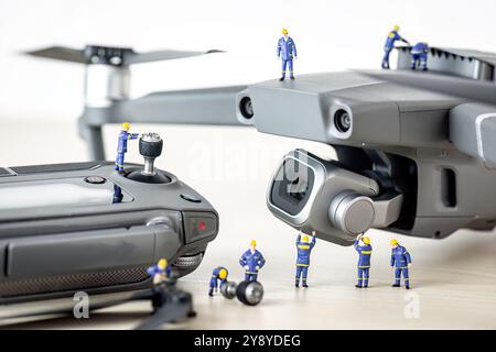 Ingénieurs miniatures travaillant sur un drone et sa télécommande, effectuant la maintenance et la réparation Banque D'Images