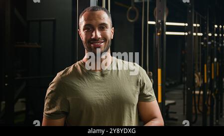 Fort musclé souriant entraîneur de fitness personnel Guy Afro-américain homme sportif athlète bodybuilder boxer coureur jogger posant dans le gymnase du club de sport Banque D'Images