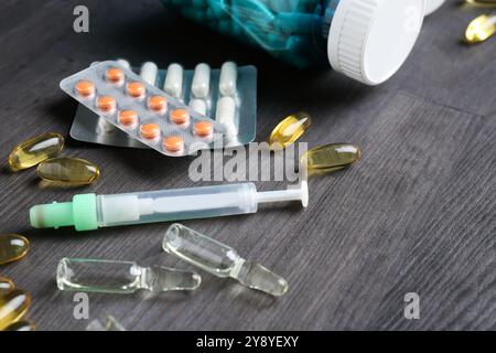 Pharmacien. Différentes pilules, seringue et ampoules sur table en bois gris, gros plan Banque D'Images