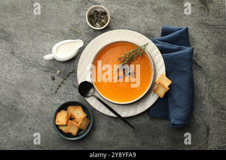 Délicieuse soupe de citrouille aux épices servie sur table texturée grise, pose à plat Banque D'Images