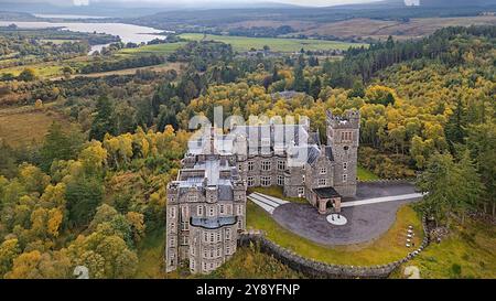 Château de Carbisdale Sutherland Écosse entouré d'arbres en automne Kyle of Sutherland au loin Banque D'Images