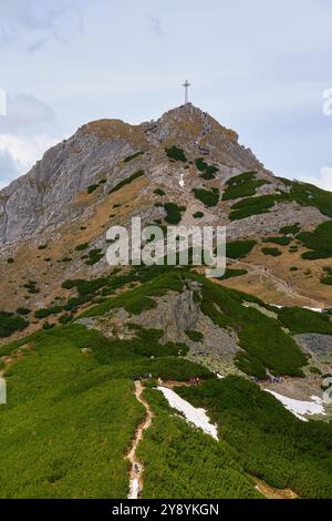 Sentier de randonnée accidenté menant au sommet de la montagne avec une grande croix sous ciel nuageux. Montagnes des Tatra à Zakopane, Pologne. Sommet de la montagne Giewont. Natura Banque D'Images