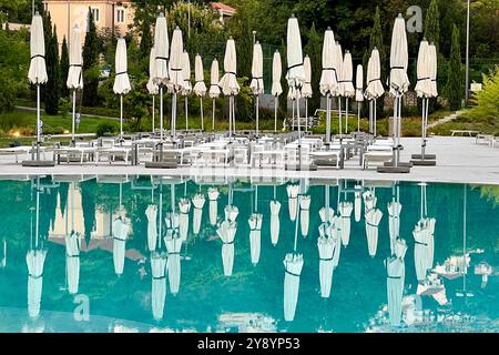 Omberellas et rayons de soleil emballés pour la soirée reflétée dans la piscine. Hôtel Sheraton, Sebreno près de Dubrovnik, Croatie Banque D'Images