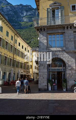 Une rue calme ombragée avec des bâtiments traditionnels itailiens et un fond de montagne. Riva Del Garda, Trentin, Italie. Banque D'Images