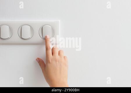 Main femelle appuyant sur l'interrupteur de lumière on ou OFF pour économiser de l'énergie à la maison Banque D'Images