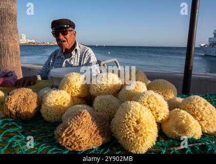 Un homme vendant des éponges naturelles sur le front de mer à Paphos Harbour, Chypre. Banque D'Images