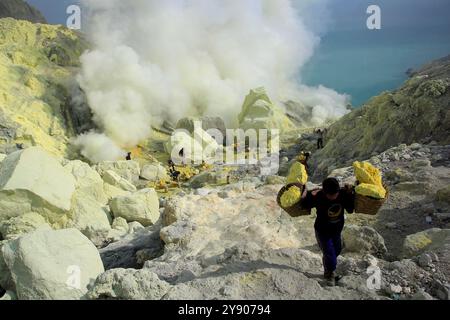 Mineurs de soufre dans le cratère Ijen. Le cratère devrait produire plus de 36 millions de mètres cubes de chlorure d'hydrogène et de soufre Banque D'Images