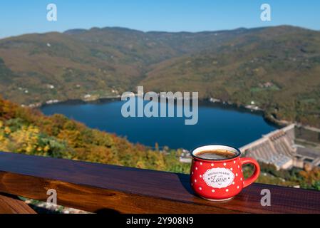 Tasse de café sur le belvédère Zelenika avec vue sur le lac Perucac et le barrage de barrière d'eau sur la rivière Drina en Serbie par un jour d'automne ensoleillé. Banque D'Images