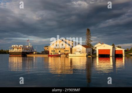 Bâtiments de village balnéaire dans une lumière chaude au coucher du soleil. Lumière très douce, reflets sur l'eau et nuages spectaculaires dans le ciel. Les concepts pourraient inclure la vie Banque D'Images