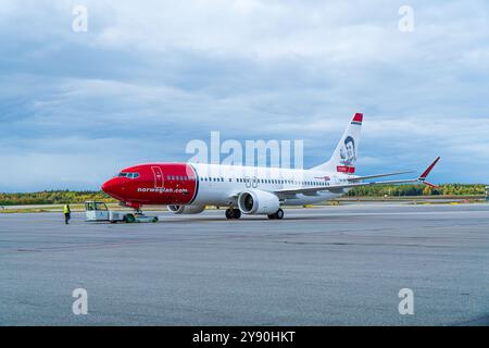 Boeing 737-800 norvégien à l'aéroport de Stockholm Arlanda sur l'aire de trafic, en repoussage. Nuageux, lumière vive. Banque D'Images