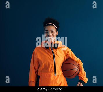 Joueur de basket-ball professionnel souriant et confiant portant des vêtements de sport orange regardant son appareil photo Banque D'Images