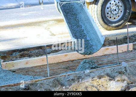 Le malaxeur à béton verse du béton frais sur des barres renforcées pour le nouveau trottoir Banque D'Images