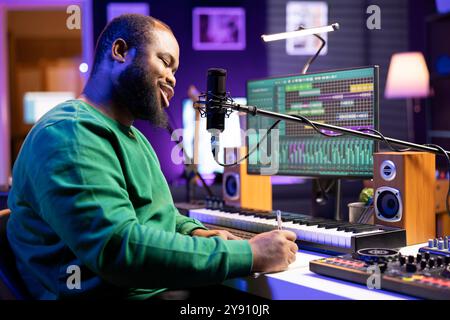 Jeune auteur-compositeur composant une nouvelle chanson dans son home studio, pensant à de nouveaux mots pour correspondre aux rimes. Artiste musicien écrivant vers le bas pour créer une bande sonore, la production musicale. Banque D'Images