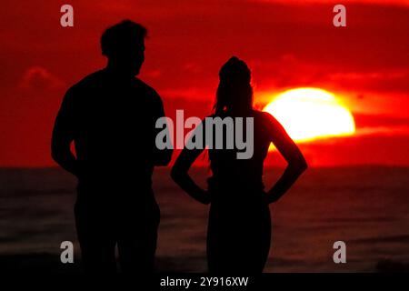 Île de Palms, États-Unis. 07 octobre 2024. Un couple, silhouetté par le lever du soleil, s’arrête pour regarder sur la plage de Wild Dunes Resort, le 7 octobre 2024 à Isle of Palms, Caroline du Sud. Crédit : Richard Ellis/Richard Ellis/Alamy Live News Banque D'Images