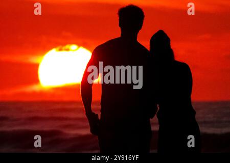 Île de Palms, États-Unis. 07 octobre 2024. Un couple, silhouetté par le lever du soleil, s’arrête pour regarder sur la plage de Wild Dunes Resort, le 7 octobre 2024 à Isle of Palms, Caroline du Sud. Crédit : Richard Ellis/Richard Ellis/Alamy Live News Banque D'Images