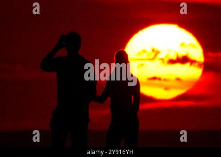 Île de Palms, États-Unis. 07 octobre 2024. Un couple, silhouetté par le lever du soleil, s’arrête pour regarder sur la plage de Wild Dunes Resort, le 7 octobre 2024 à Isle of Palms, Caroline du Sud. Crédit : Richard Ellis/Richard Ellis/Alamy Live News Banque D'Images