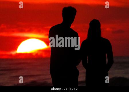 Île de Palms, États-Unis. 07 octobre 2024. Un couple, silhouetté par le lever du soleil, s’arrête pour regarder sur la plage de Wild Dunes Resort, le 7 octobre 2024 à Isle of Palms, Caroline du Sud. Crédit : Richard Ellis/Richard Ellis/Alamy Live News Banque D'Images