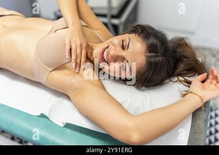 Beauté cacucasienne femme couchée sur brancard souriante satisfaite après le traitement d'épilation avec la technologie laser Banque D'Images