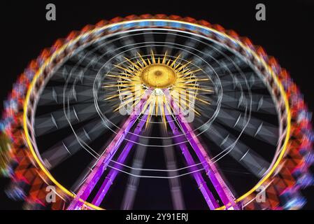 Grande roue illuminée la nuit dans des couleurs néons vives sur un ciel sombre, Cannstatter Volksfest, Wasen, Bad Cannstatt, Stuttgart, Baden-Wuerttember Banque D'Images