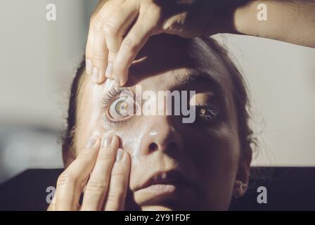 Gros plan d'un examen des yeux avec les mains ouvrant l'œil Banque D'Images