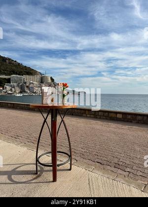 Une table avec un bouquet de tulipes et une pile de menus sur le talus de Rafailovici à la journée ensoleillée, Monténégro Banque D'Images