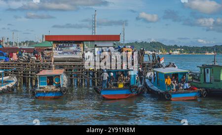 Balikpapan, Indonésie - 26 juin 2024. Au petit port de plaisance, ou Pelabuhan Klotok, les passagers embarquent sur le long ferry, certains apportant leur moto Banque D'Images