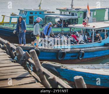 Balikpapan, Indonésie - 26 juin 2024. Certains passagers de ferry incluent également leurs motos pour être transportées par le long bateau ferry en bois.. Banque D'Images