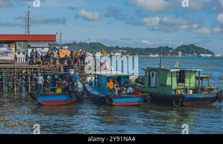 Balikpapan, Indonésie - 26 juin 2024. Au petit port de plaisance, ou Pelabuhan Klotok, les passagers embarquent sur le long ferry, certains apportant leur moto Banque D'Images