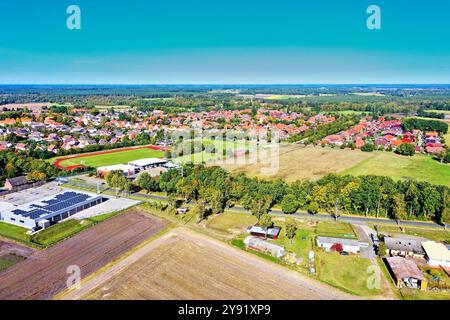 Vue aérienne d'un petit village en allemagne, montrant des maisons, un terrain de sport, des champs agricoles et une forêt en arrière-plan Banque D'Images