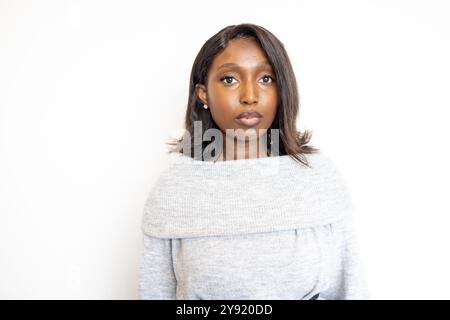 Femme confiante avec les cheveux courts respire le calme dans le pull gris sur fond blanc, semble chic et élégant Banque D'Images