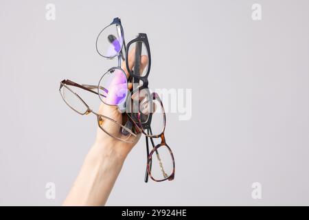 main tenant beaucoup de lunettes pour la vision sur fond blanc, bon concept de vision, sélection de lunettes, soins de lunettes, problème de vision Banque D'Images