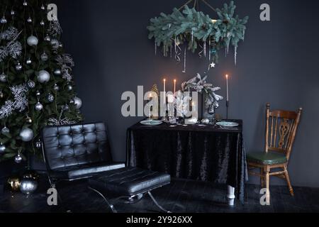 Intérieur élégant du nouvel an dans un style sombre, arbre du nouvel an avec des jouets du nouvel an et table décorée dans un style sombre Banque D'Images