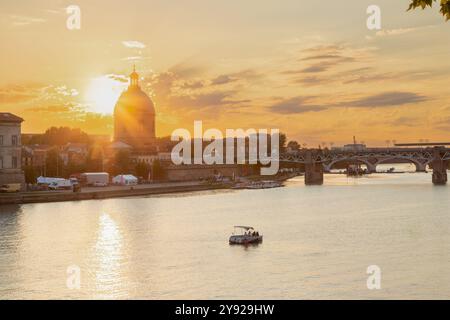 Coucher de soleil doré sur la Garonne avec vue sur le pont piétonnier Saint-Pierre, la place Saint-Pierre et la tombe de l'hôpital vu de la rivière Banque D'Images