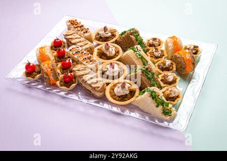 Un plateau magnifiquement arrangé de mini-hors-d'œuvre savoureux avec du pain, des herbes et des tomates cerises fraîches. Banque D'Images