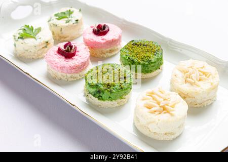 Mini-hors-d'œuvre avec des garnitures colorées, garnies d'herbes et de noix, servis sur une assiette blanche Banque D'Images