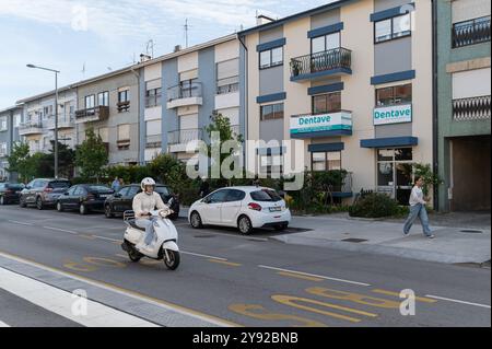 Aveiro, Portugal - 11 septembre 2024 : Un motocycliste navigue dans une voiture garée le long d'une rue résidentielle. Banque D'Images