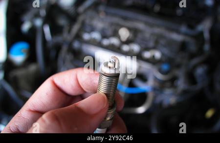 Bougies d'allumage sales et endommagées , gros plan de vieilles bougies d'allumage du moteur à combustion de voiture dans les mains du mécanicien de voiture , concept de réparation de voiture Banque D'Images