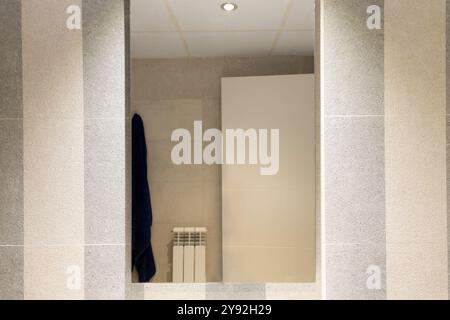 Un miroir de salle de bain avec une serviette suspendue dessus. La chambre a un style moderne et minimaliste Banque D'Images