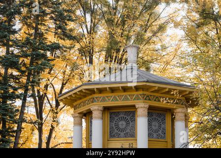 Gazebo sur le territoire de 'Expocenter of Ukraine' (VDNG). Toit d'un petit bâtiment en forme de tour avec colonnes blanches et corniche jaune, arbres jaunes d'automne. Banque D'Images