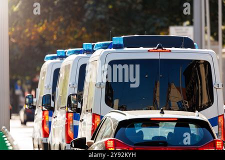 Vue arrière de la scène de nombreux fourgonnettes de police allemandes conduisent dans le centre de feux de circulation de la route urbaine de la ville le jour ensoleillé. Circulation de sécurité civile de la loi d'urgence Banque D'Images