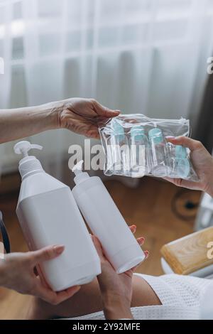 Cosmétologue montre au client un produit cosmétique et des bouteilles en plastique de voyage, maquette de bouteille de crème. Photo de haute qualité Banque D'Images